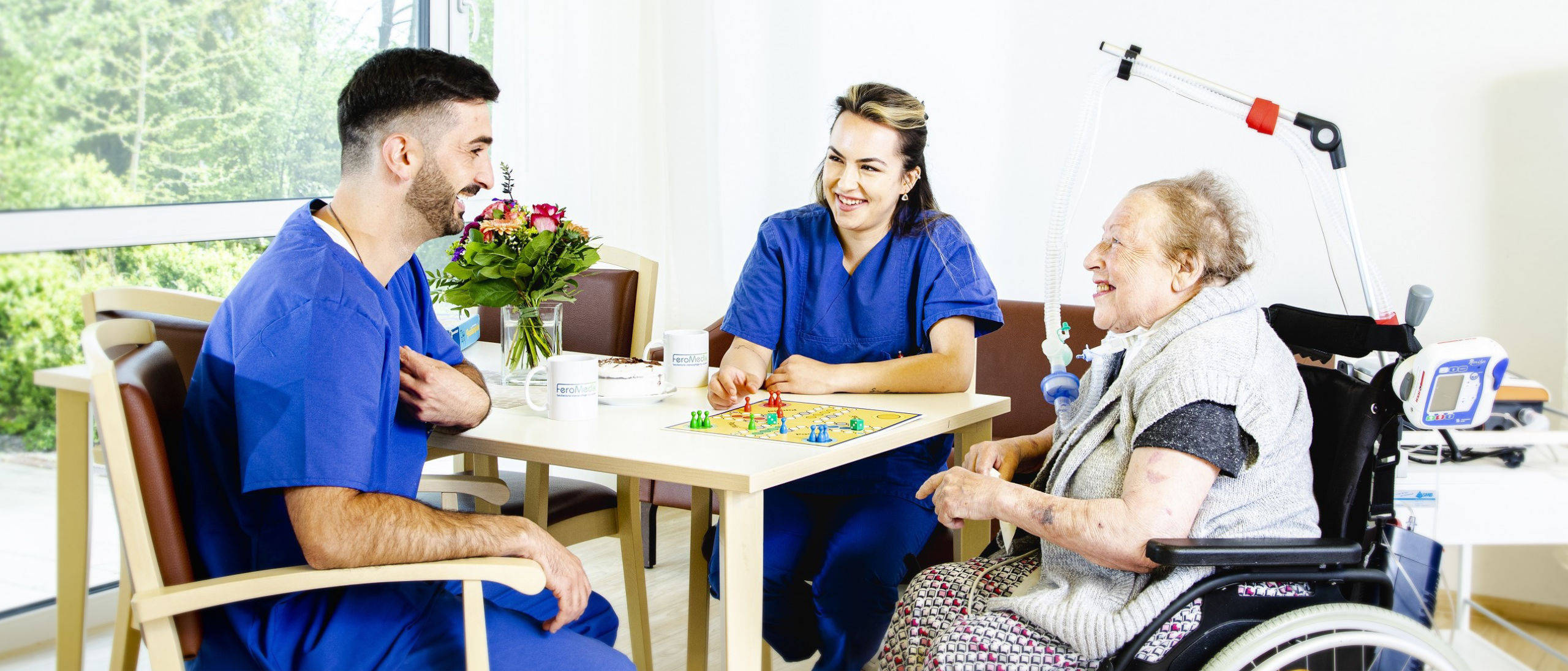 Zwei Pflegekräfte sitzen mit Patientin am Tisch